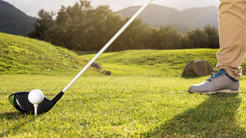 Closeup of man’s foot as he practices golf on the field