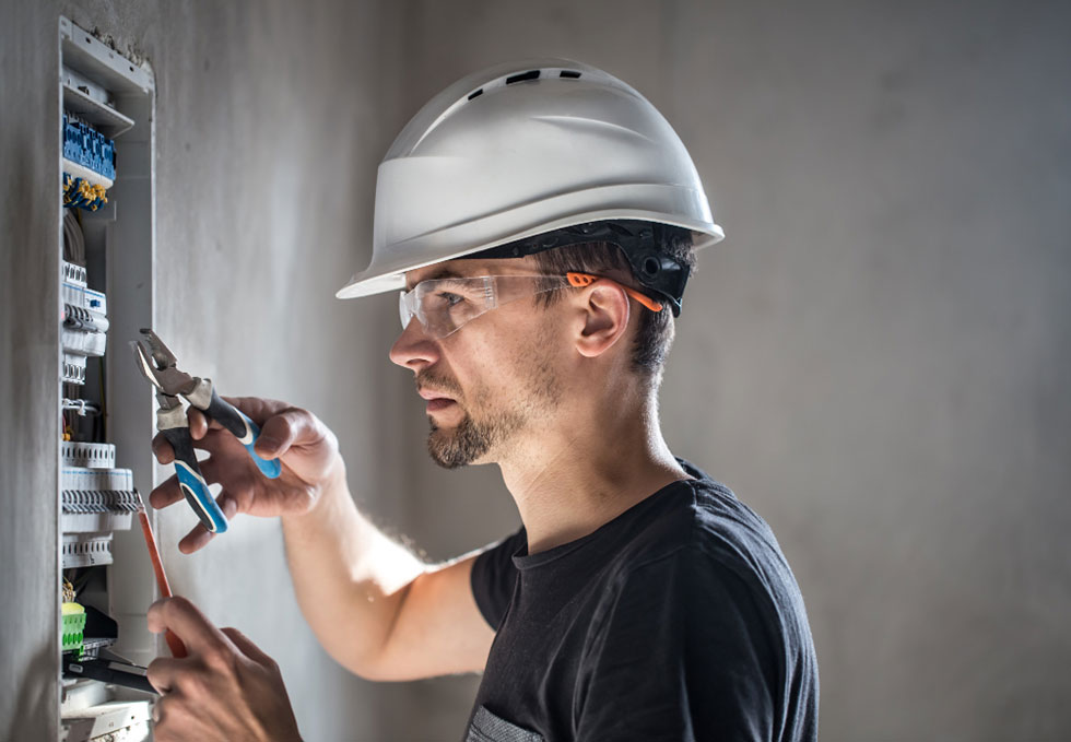 Electrical technician working with switchboard fuses