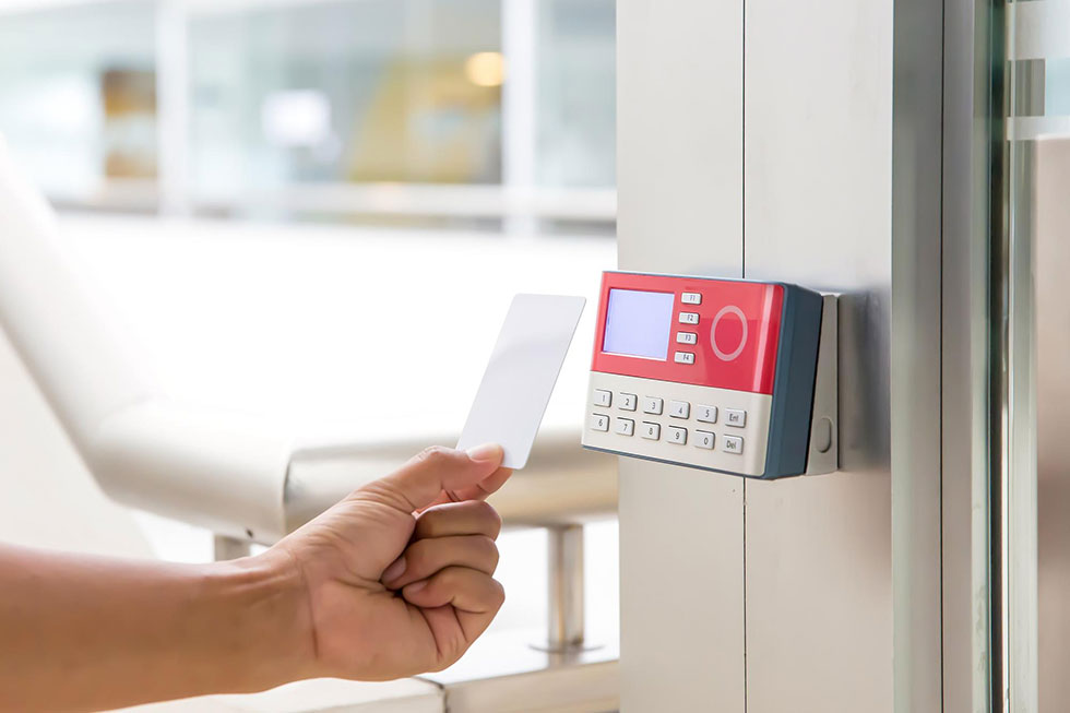 Hand holding proximity card about to tap onto card reader at building door