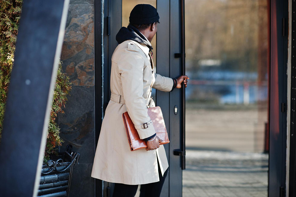 Man holding a folder about to open building door