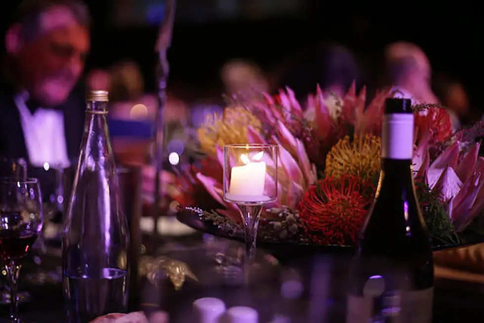 bottles in the foreground, formally dressed people in back at a party