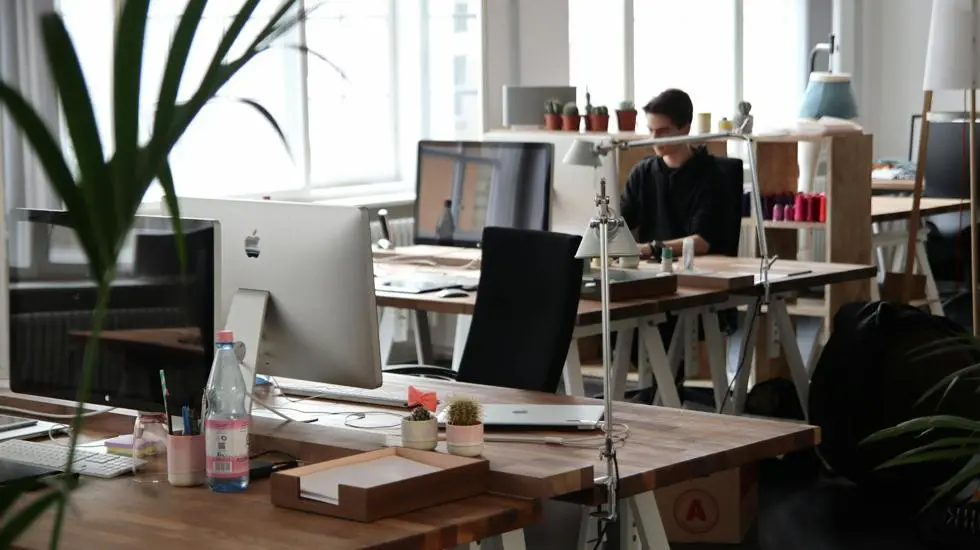 office with desks, one guy at a desk, face cut off by lamp